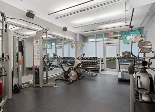 a gym with weights and cardio equipment on the floor and windows