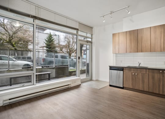 an empty living room with a large window and a kitchen