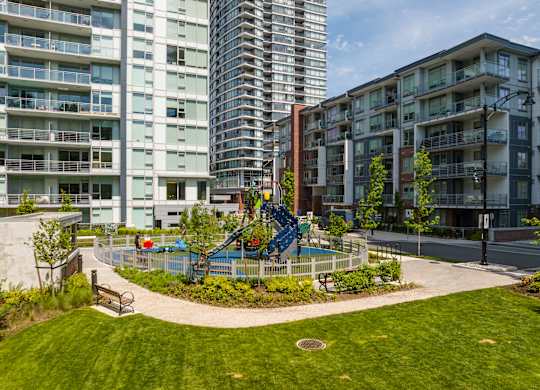 A playground with a blue slide is surrounded by apartment buildings.