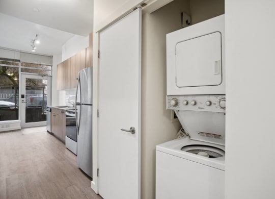a white washer and dryer in a kitchen with a door to the laundry