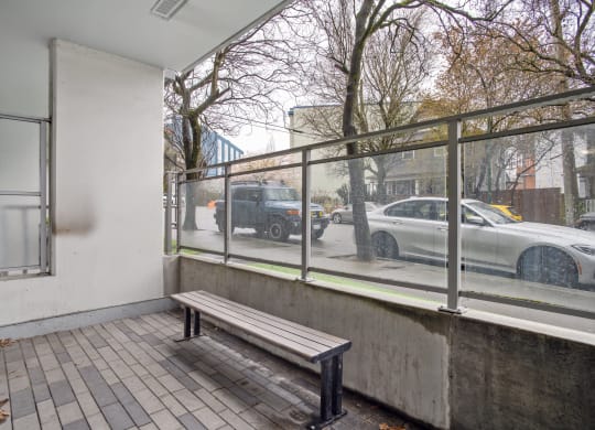 a bench on a sidewalk next to a building with a window