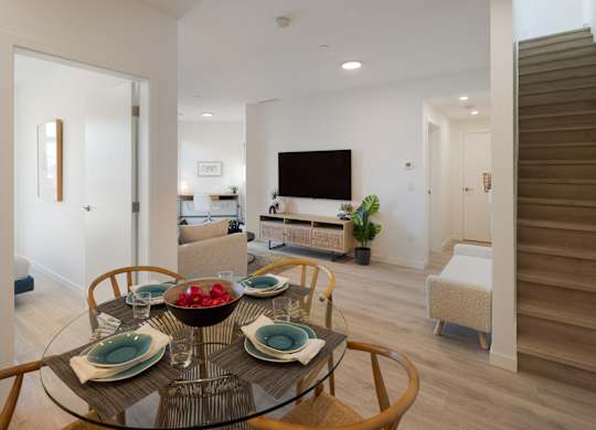 A modern dining room with a glass table set for four.