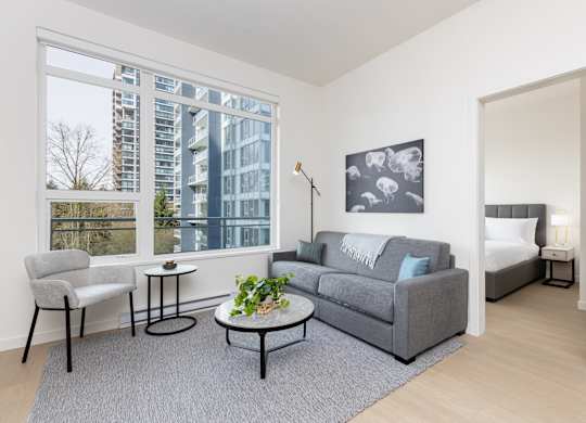 A grey couch with a white throw is in the living room.