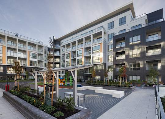 A modern apartment complex with a playground in the courtyard.