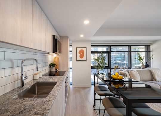 A modern kitchen with a granite countertop and a dining table set for two.
