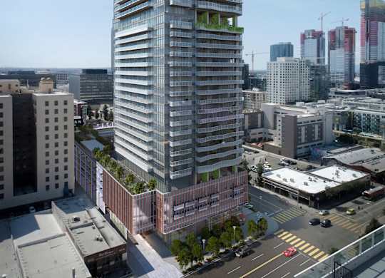A tall, modern building with a glass facade stands in the middle of a cityscape.