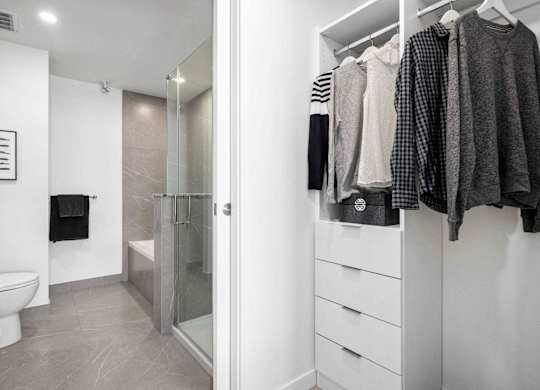 A white bathroom with a walk in shower and a towel hanging on the wall.