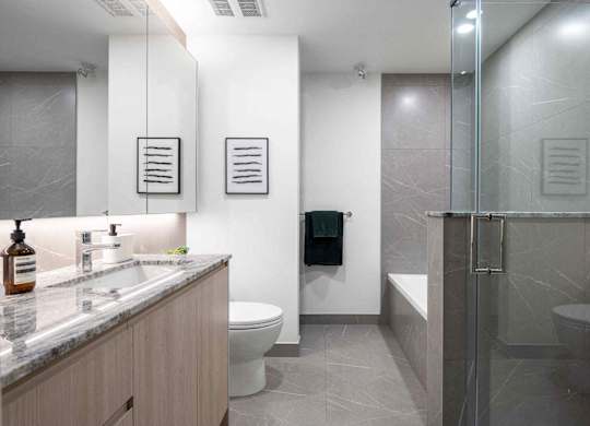 A bathroom with a toilet, sink, and mirror.