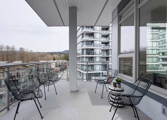 A balcony with chairs and a table with a plant on it.