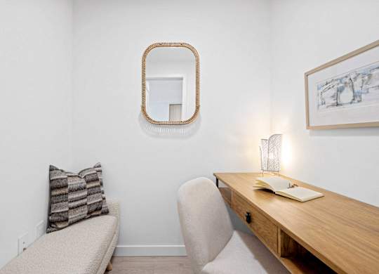 A white room with a wooden desk and a chair.