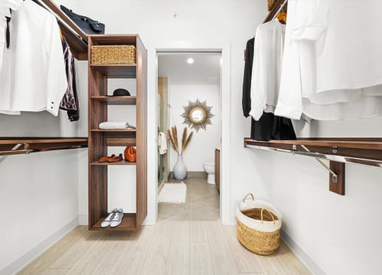 a walk in closet with wooden shelves and a door to the bathroom