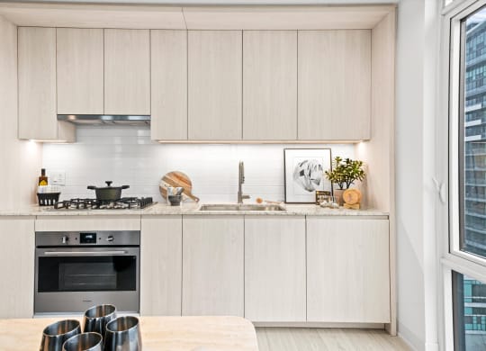 a kitchen with white cabinets and a table and a window
