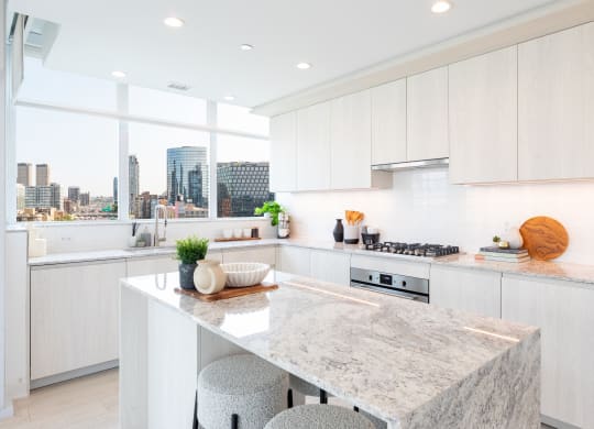a kitchen with white cabinets and a large island with two stools