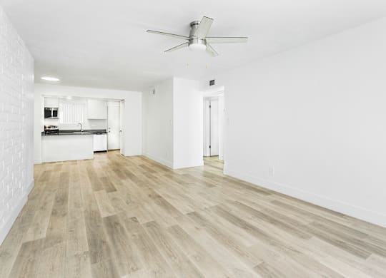 A room with a ceiling fan and wooden flooring.