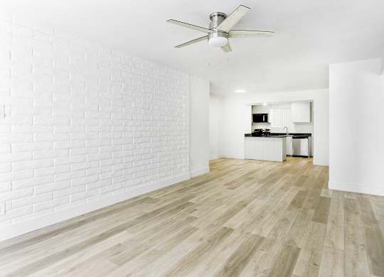 A room with a ceiling fan and wooden flooring.