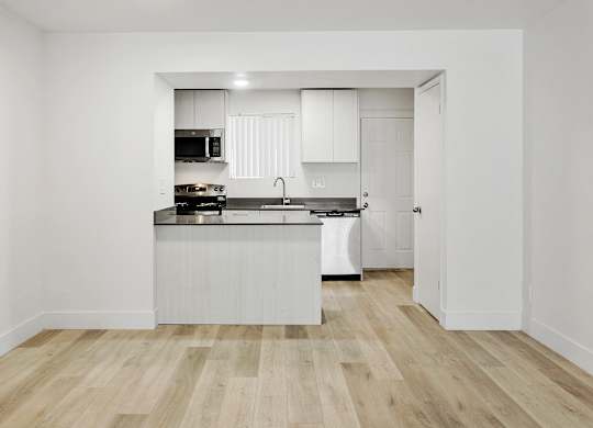 A kitchen with white cabinets and a wooden floor.