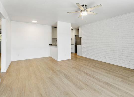 A room with a ceiling fan and wooden flooring.