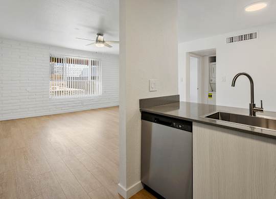A kitchen with a stainless steel dishwasher and a black trash can.