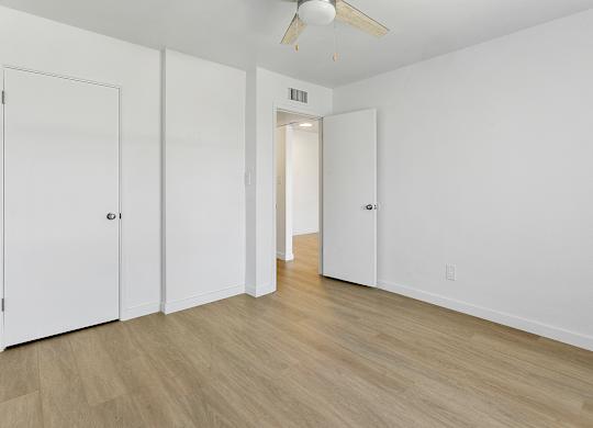 A room with a ceiling fan and white walls.