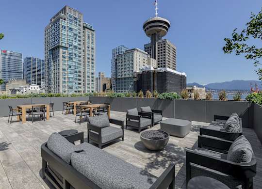 A rooftop patio with a view of the city skyline and a tall tower.
