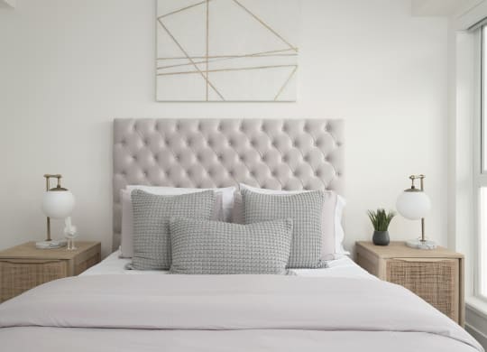 a white bedroom with a bed with pillows and a geometric painting on the wall
