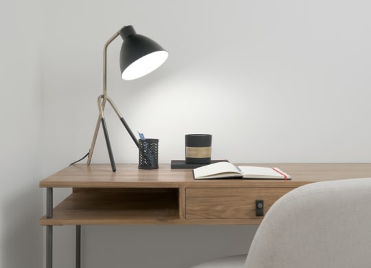 a desk with a lamp and a chair in a room