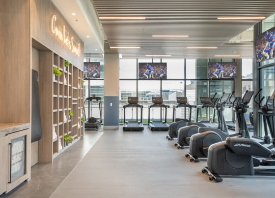 a row of treadmills and elliptical trainers in a gym
