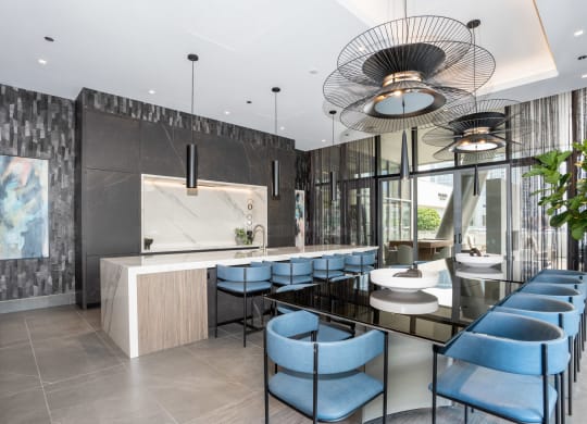 a kitchen and dining area with blue chairs and a long black table