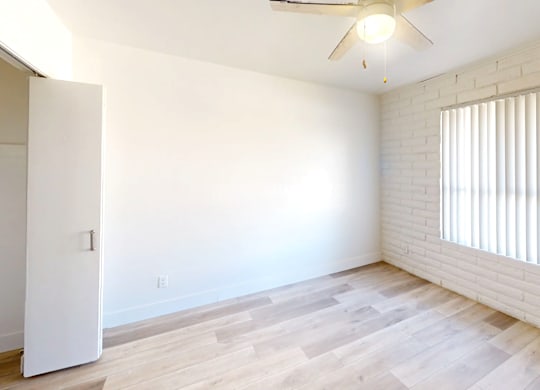 A room with a ceiling fan and a window with blinds.