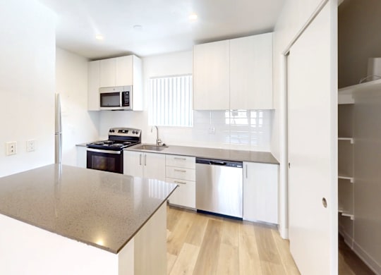 A modern kitchen with a stainless steel countertop and white cabinets.