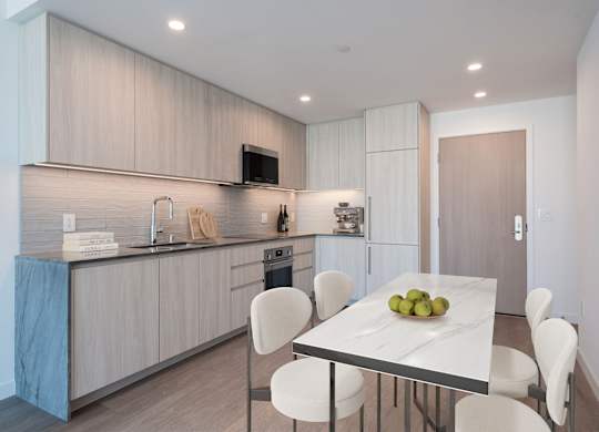 A modern kitchen with a dining table set with fruit.