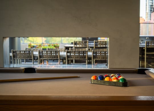 a pool table with a view of a dining room in the background