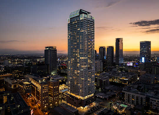 A cityscape at dusk with a tall building in the foreground.