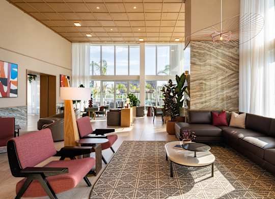 A large room with a long couch and a table with a vase on it.