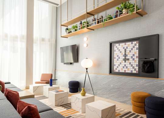 A modern living room with a grey sofa, a television, and a shelf with plants.