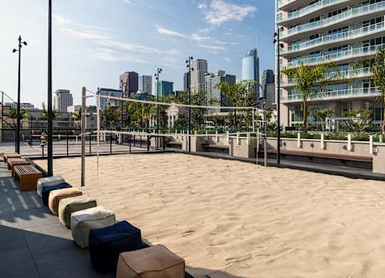 A sandy beach area with benches and a city skyline in the background.