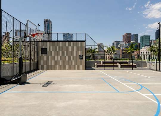 A basketball court with a fence and a building in the background.