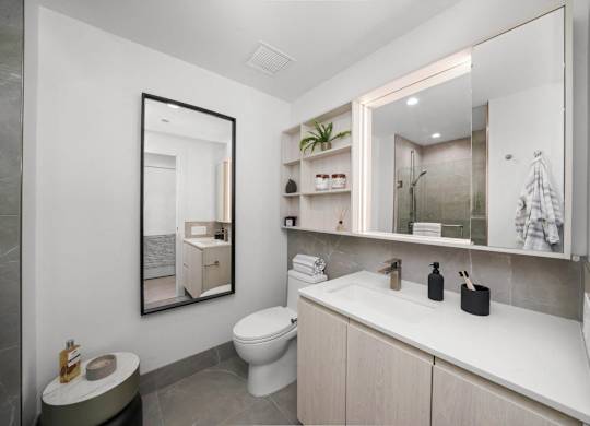 A bathroom with a toilet, sink, and mirror.