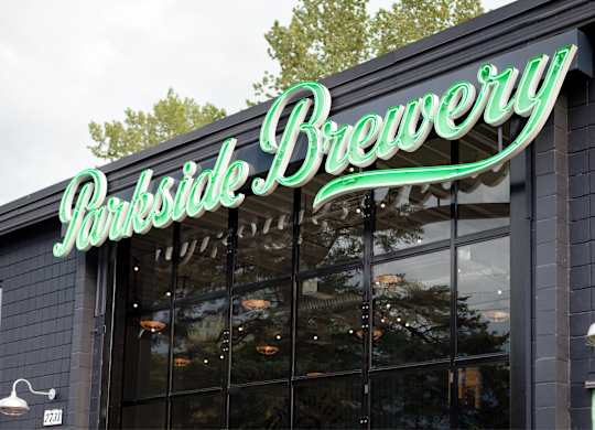 A brewery sign with a green neon light.