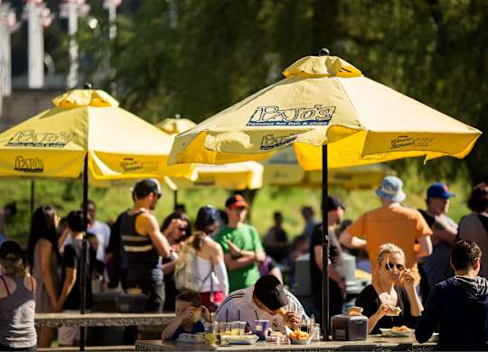 A group of people are sitting at tables under yellow umbrellas.