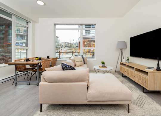 A modern living room with a large couch, a flat screen TV, and a wooden cabinet.