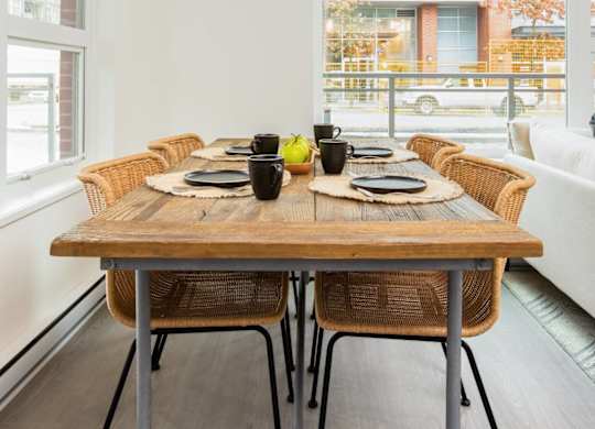 A dining table with chairs and a tablecloth is set for a meal.
