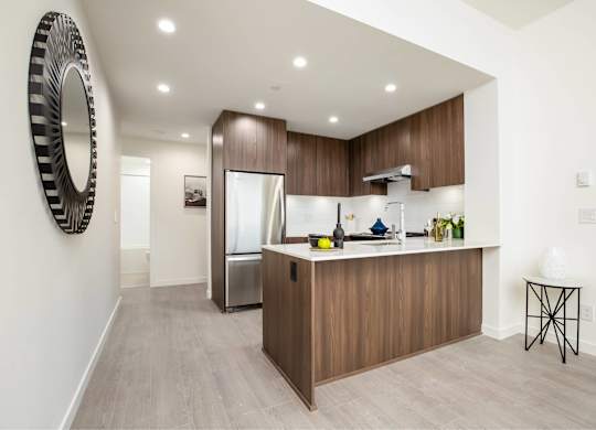 A modern kitchen with wooden cabinets and a large mirror on the wall.