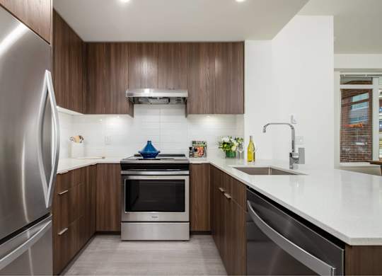 A modern kitchen with a stainless steel refrigerator and wooden cabinets.