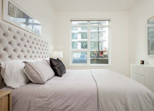 A bedroom with a large bed and a window overlooking a cityscape.