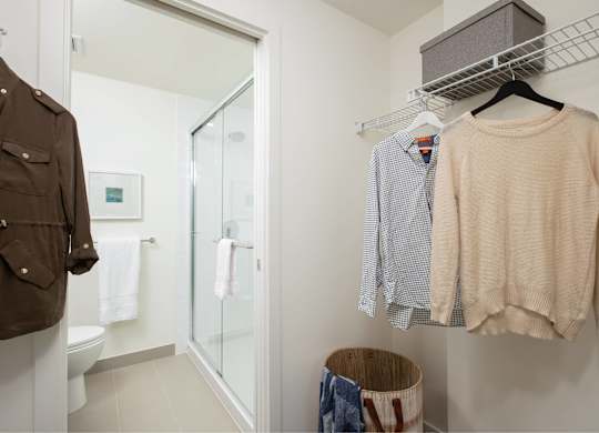 A brown jacket is hanging on a rack next to a white towel.