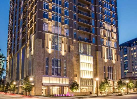A tall building with many windows is lit up at night.
