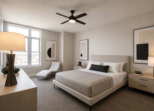 A well-lit bedroom with a large bed, a chair, and a ceiling fan.