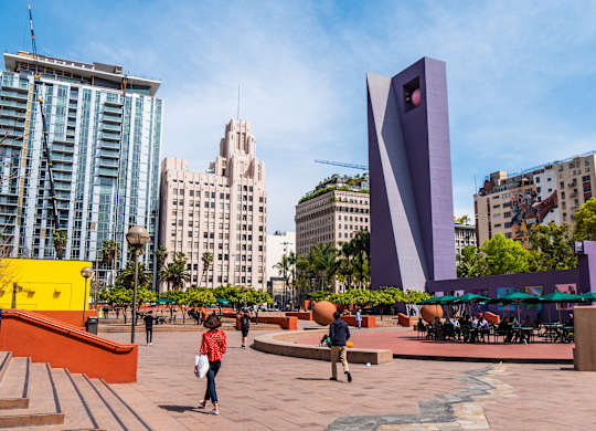A woman in a red shirt is standing in front of a large purple sculpture.