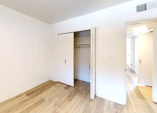 A room with a white wall and a wooden floor with a white door.